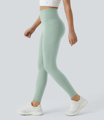Person wearing light green leggings and white sneakers on a plain background